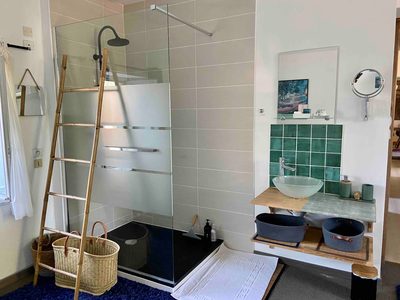 Douche à l'italienne ouverte sur la chambre Hellébore, double vasque sur meuble en bois et échelle porte-serviettes.
